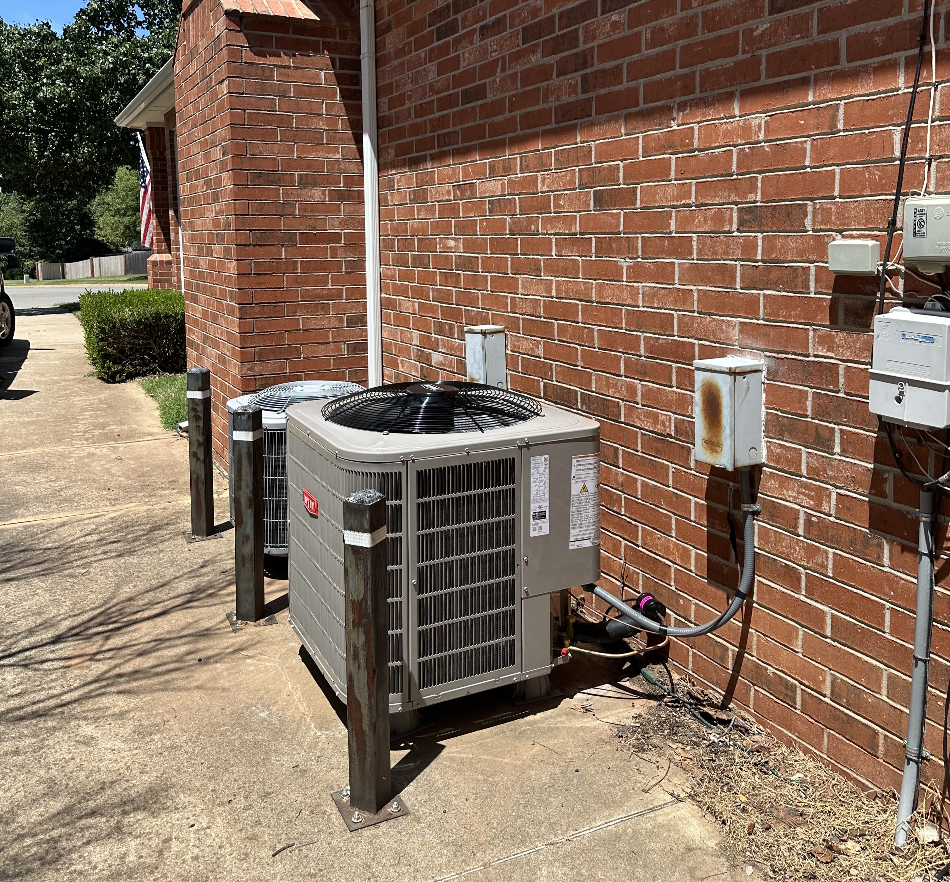 Two outdoor central air conditioning units installed on concrete pads next to a building, ready for operation.